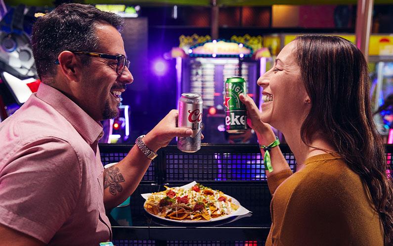 A mom and a dad enjoying an alcoholic beverage and a plate of nachos on the games floor.