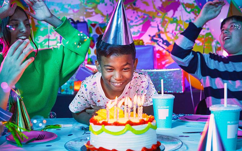 A young boy blowing out the candles on his birthday cake.